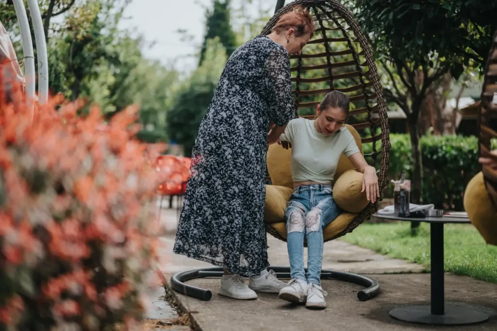 Support worker helping disabled girl get out of egg chair