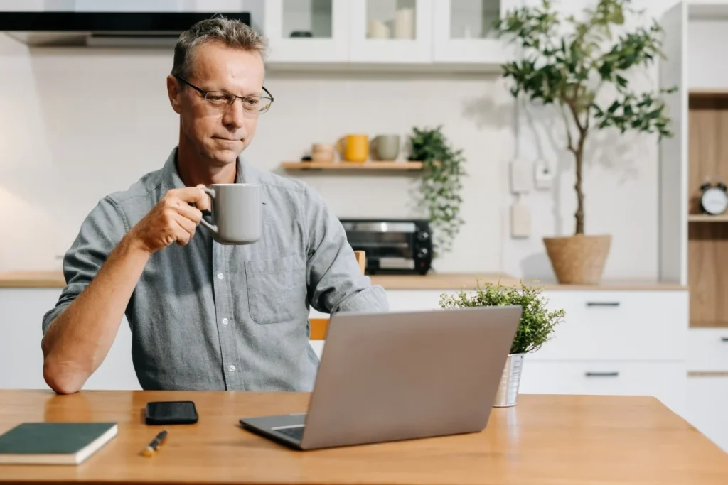 Man making NDIS referral via laptop at kitchen bench